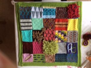 Front of lap blanket with patchwork of many different knitting techniques in seasonal colours